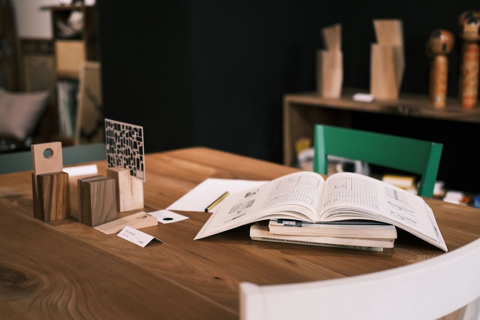 Stylish modern desk with open book, wooden decor, and minimalist design accents for a creative work environment.