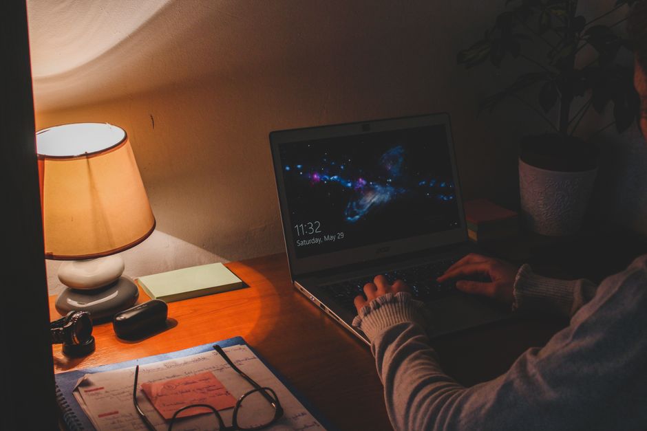 Warm ambient lighting in a workspace with a laptop and a table lamp creating a cozy atmosphere.